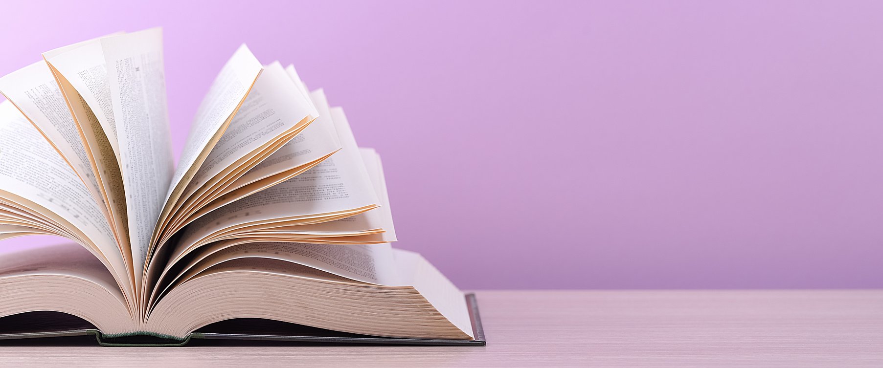 The book is open, lying on the table, sheets fanned out on a pink background.