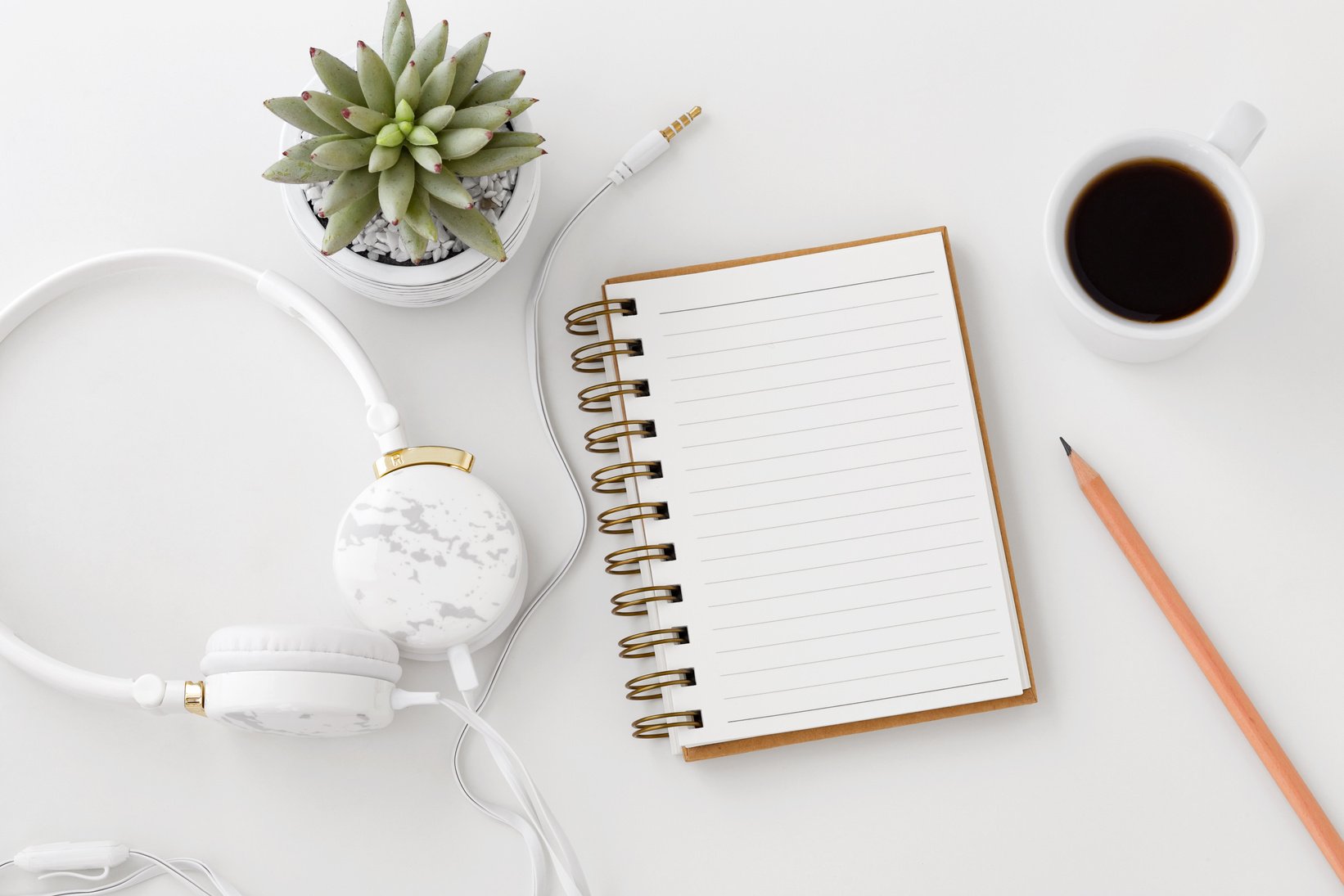 Headphones with notebook on white desk